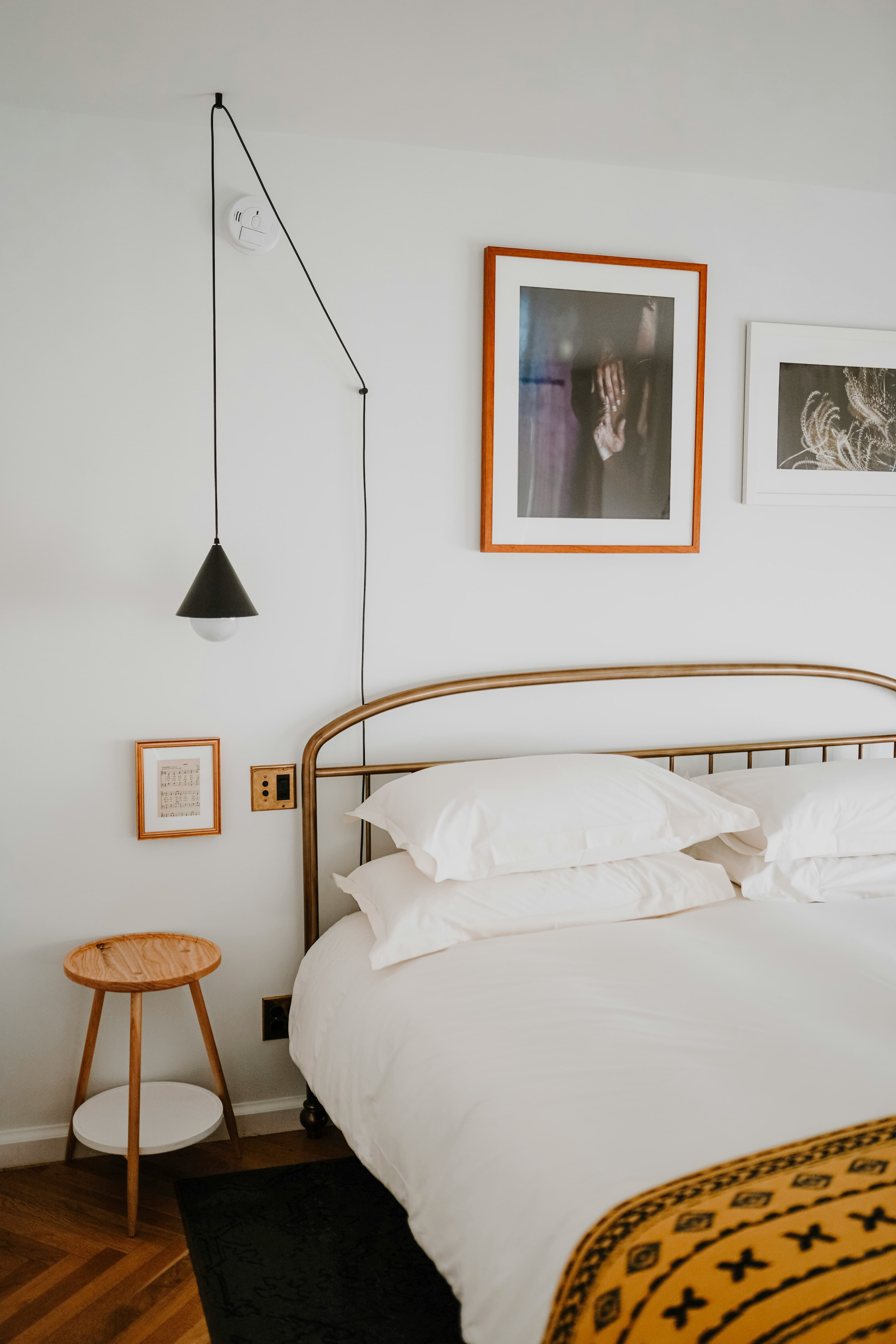 Brass bed with white linen beside a wall-mounted reading lamp